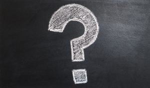 A large question mark drawn in white chalk on a blackboard.