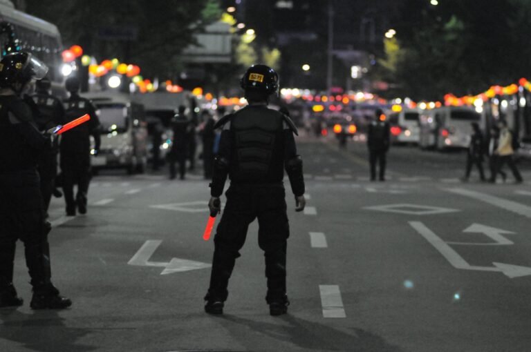 Uniformed officers standing on a city street at night.