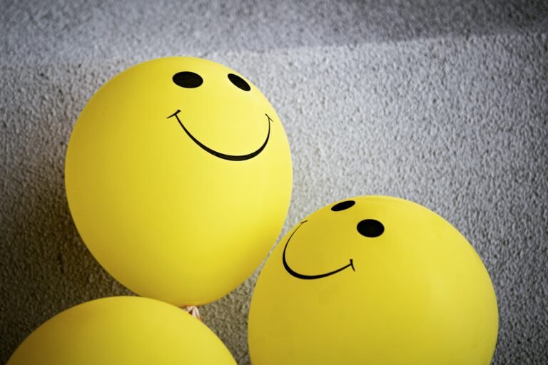 Yellow balloons with smiling faces against a gray wall.